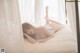 A woman laying on a bed in a white lingerie.