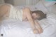 A woman laying on a bed in a white dress.