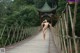 A naked woman walking across a wooden bridge.