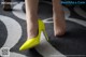 A close up of a woman's feet wearing yellow high heels.