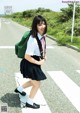 A young woman in a school uniform crossing the street.