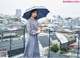 A woman standing on a balcony holding an umbrella.