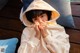 A young boy in a white hoodie sitting on a wooden bench.