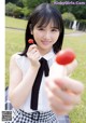 A young woman holding a red lollipop in her hand.