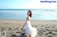 A woman in a white dress standing on a beach.