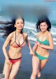 Two young women in bikinis running on the beach.