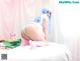 A woman with blue hair is sitting on a bed.