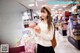 A woman standing in front of a store holding a cupcake.